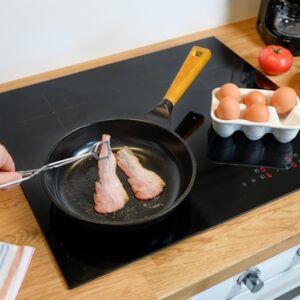 Person cooking chicken on cooktop.